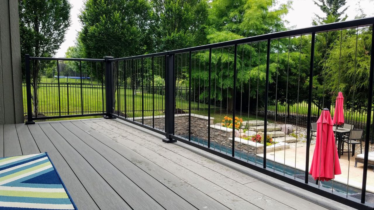 C80 Verticable Level cable rail vertical by westbury in fine texture black by westbury set infront of a pool with lush green all around c80 vertical cable complements and looks wonderful as well as alows for non-obstructed view beyond railing