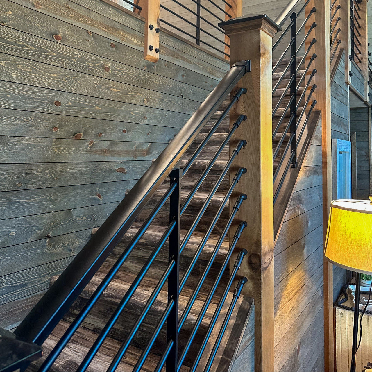 Wooden staircase with black rod railings in a home interior using Dekpro prestige top rail and 5/8" black horizontal balusters for stair/angle.