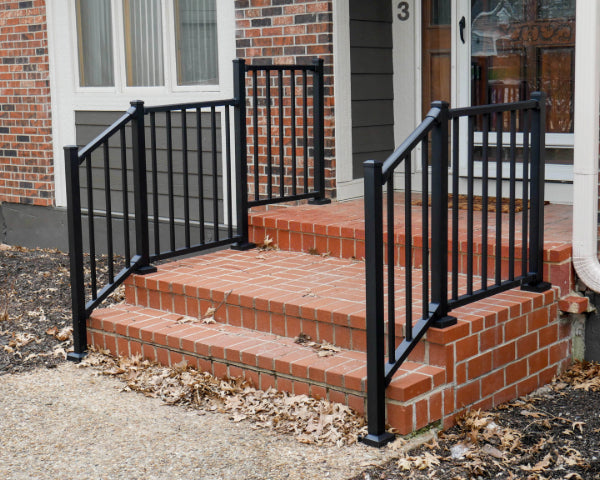 Front porch railing on brick steps with contrasting black rail that contours the steps and flattens out to the landing with a step up of level rail