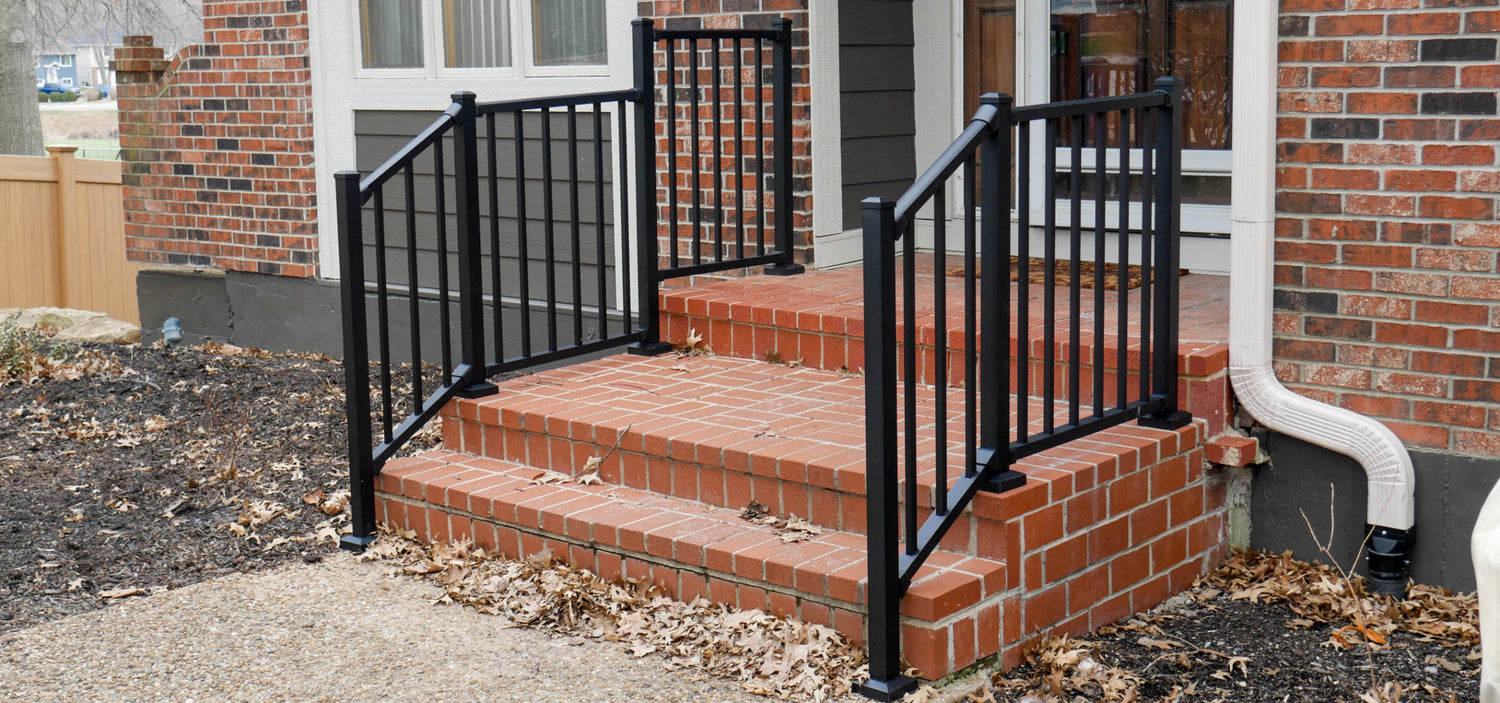 Front porch railing on brick steps with contrasting black rail that contours the steps and flattens out to the landing with a step up of level rail
