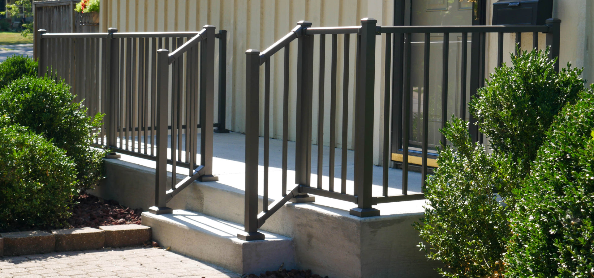 Wesbury Bronze concrete porch rail on concrete cement step for a safe outdoor patio lounging area uses aluminum porch rail with minimal two inch posts