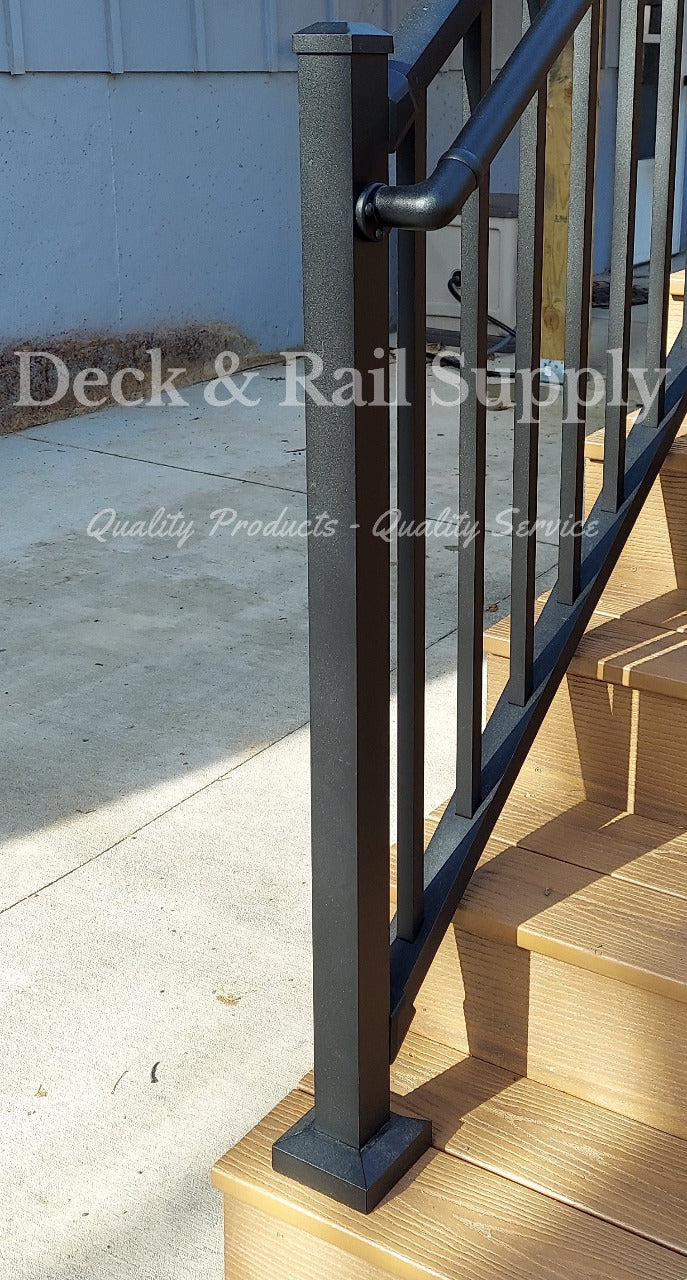 47 inch black texture stair post on composite deck stair tread at the bottom of the stair way with handrail attached to side, not included are handrails and railing.