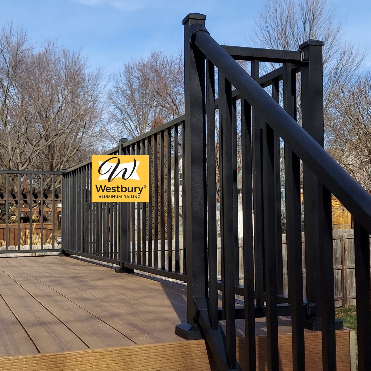 Westbury Aluminum Deck Railing, at top of stair transition to level black fine texture westbury railing an all-aluminum rail system shown in bronze texture with two inch posts atop a composite deck. 