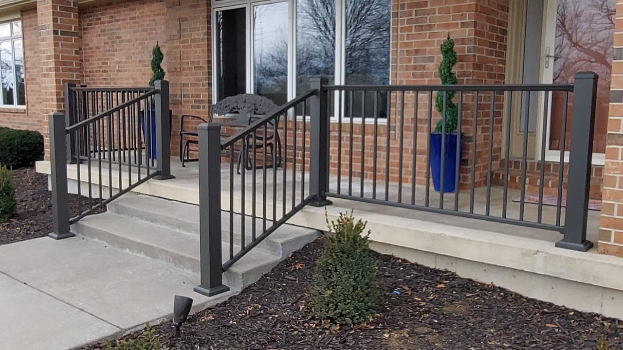 Aluminum railing like dekpro prestige in cocoa bronze infront of a house on concrete is the best option for patio railing because it can attach to the top of concrete pad for sturdy front porch railing