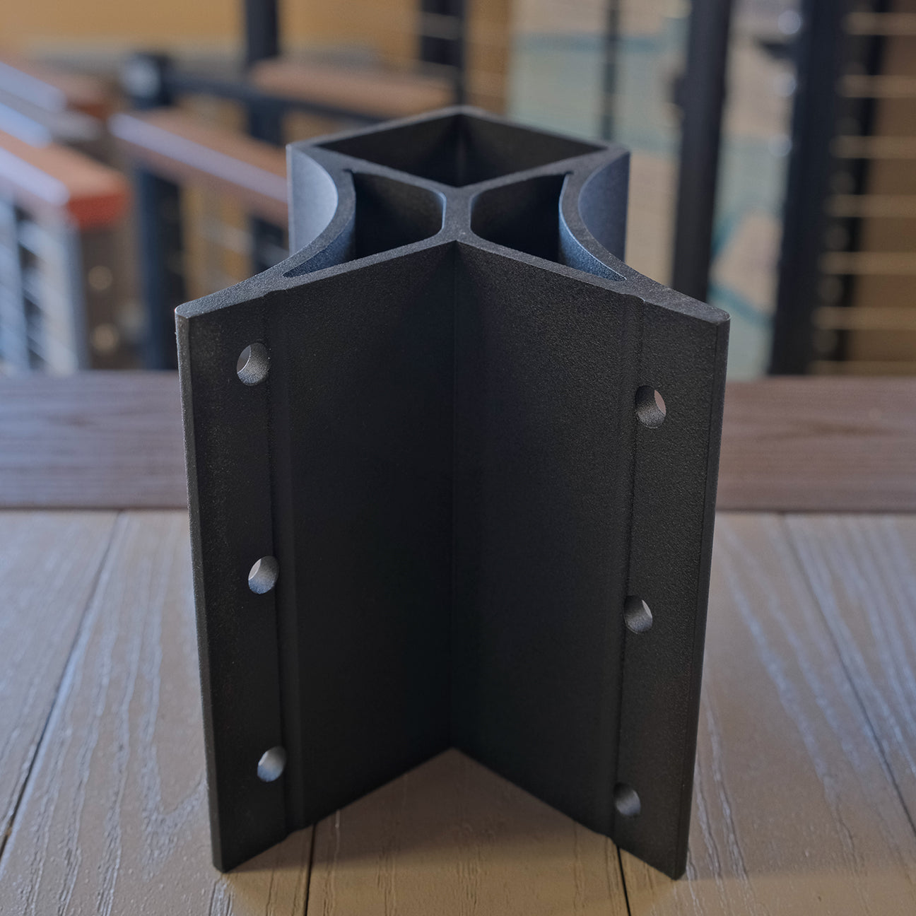 Black metal corner bracket on a wooden surface with blurred background
