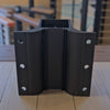 Black back of line fascia metal post bracket on a wooden surface with blurred background