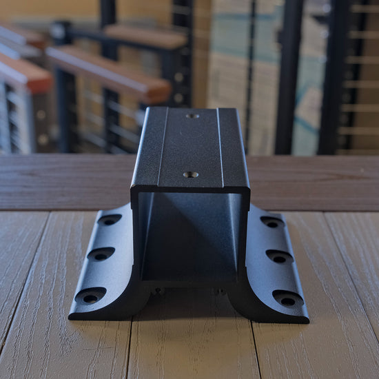 Black top of line fascia metal post bracket on a wooden surface with blurred background