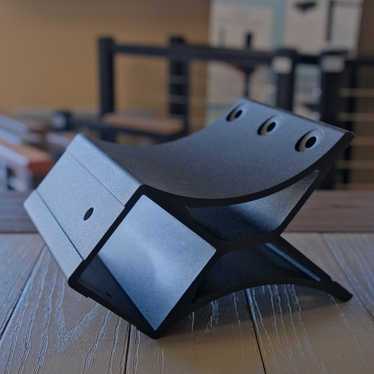 Black metal stand on a wooden surface with blurred background from a bottom angle of outside corner bracket