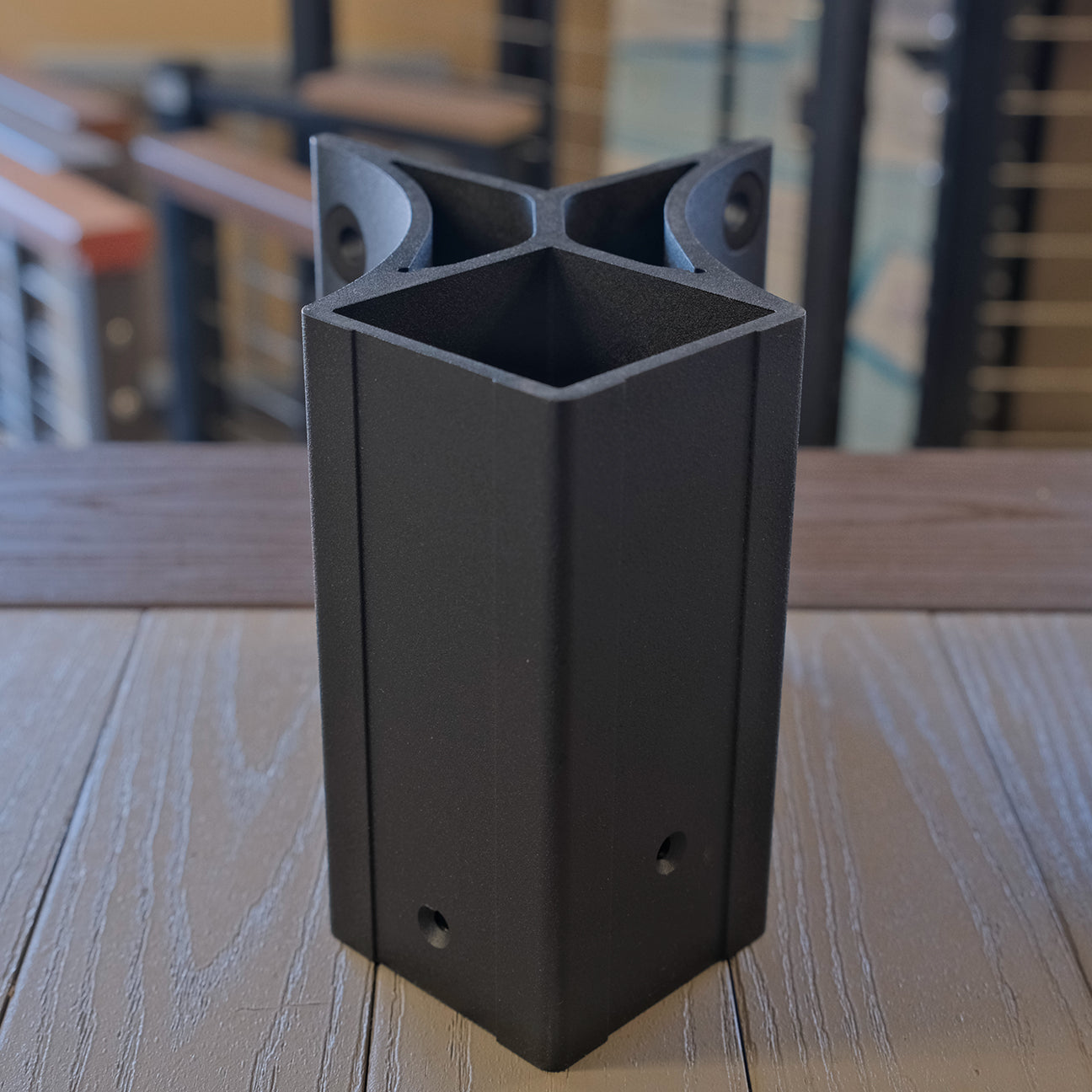 Black metal outside fascia bracket on a wooden surface with blurred background