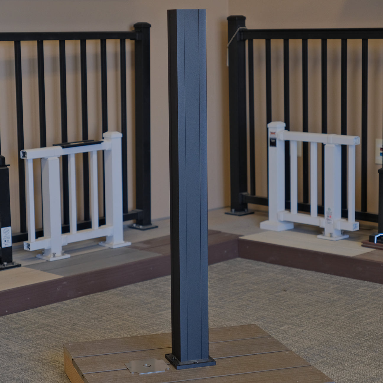 Outdoor setting with a KeyLink black aluminum 3.25 inch post and white railings against a beige wall.