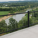Black Railing with Wire up and down over a river with lush background. KeyLink American Vertical Silver Cable Rail Kits
