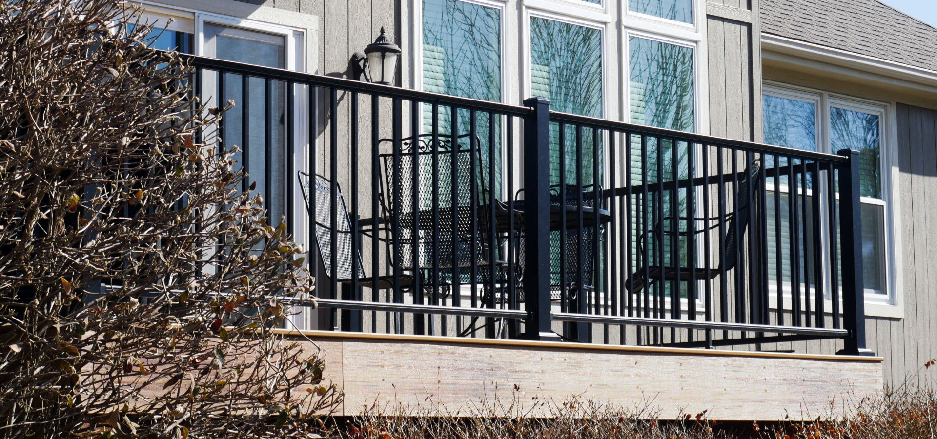 Dekpro Prestige Black handrail on sunny back deck with metal chairs and a table.