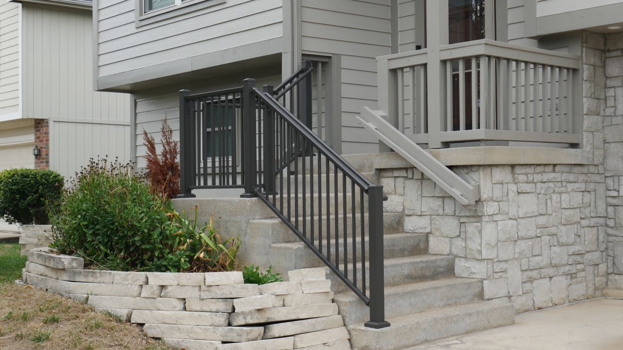 Bronze Front Porch Patio Step Railing with Graspable round continuous handrail on the front of the house aluminum handrail with base mount posts mounted to concrete or cement steps with concrete lags