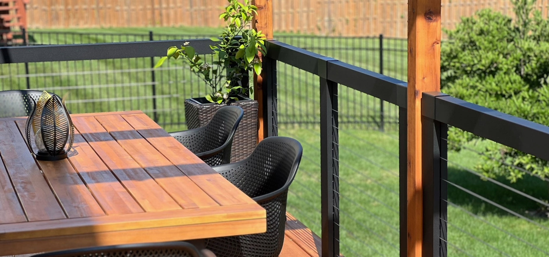 Sleek, modern cable railing with beautiful cedar posts with an outdoor seating area surround by lush, green environment.