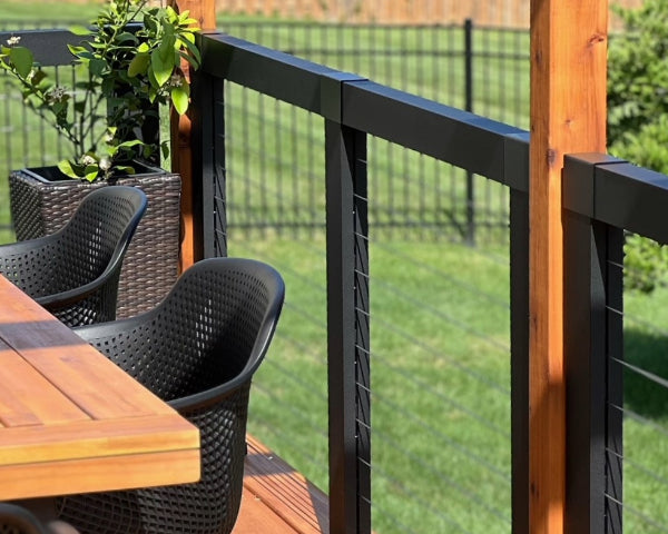 Sleek, modern cable railing with beautiful cedar posts with an outdoor seating area surround by lush, green environment.