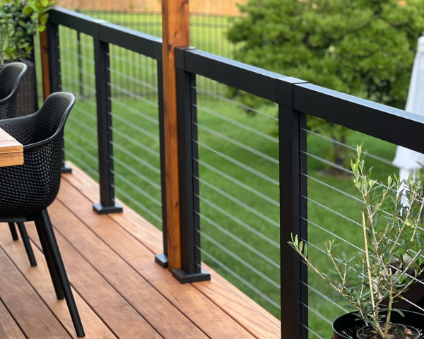 Sleek, modern cable railing with beautiful cedar posts with an outdoor seating area surround by lush, green environment.