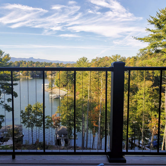C80 VertiCable beautiful background of lake and trees, walkout deck railing vertical wired stainless steel cable rail c80 with 4in x 4in posts, bright sky and mountains in the distance. Photo Credit: Megan Wilson